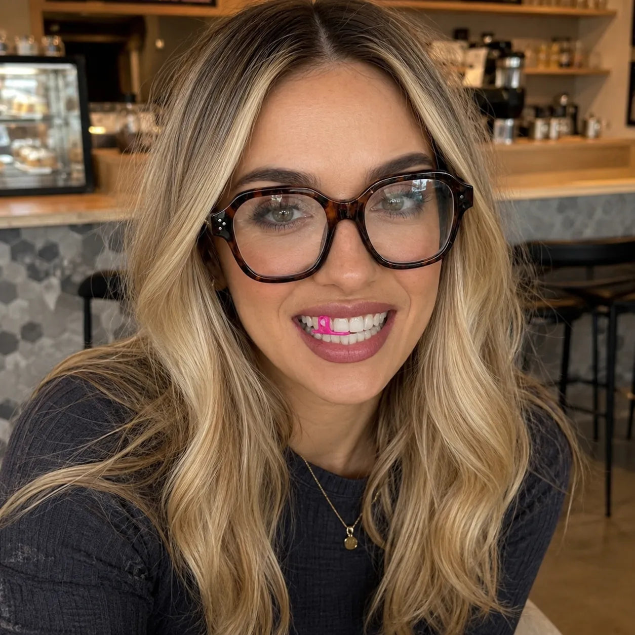 Woman smiling while using Gfloss hands-free dental floss at a café